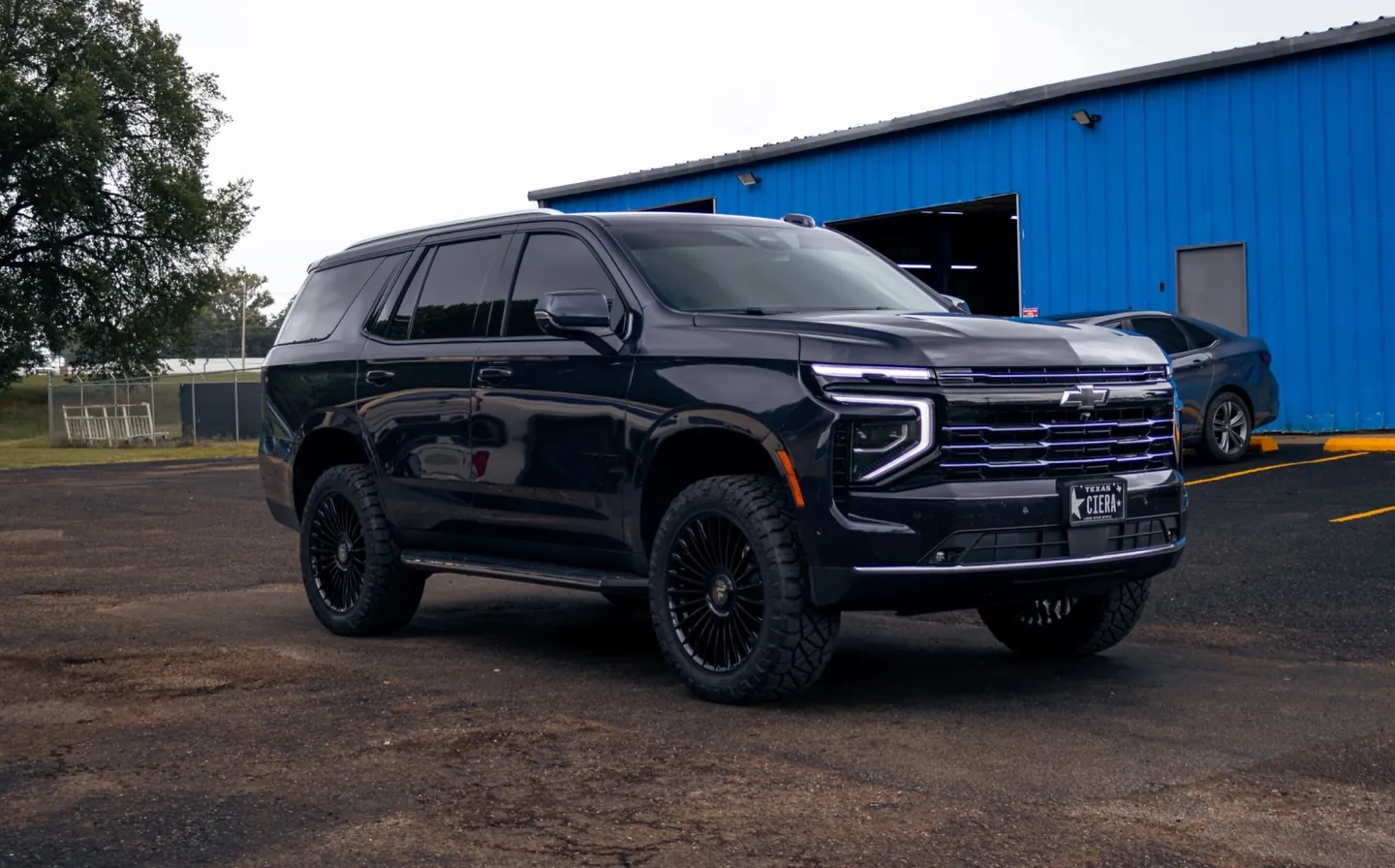 Black Chevy Tahoe on 22-inch gloss black wheels and Nitto Ridge Grappler tires outside Wheels Up Front