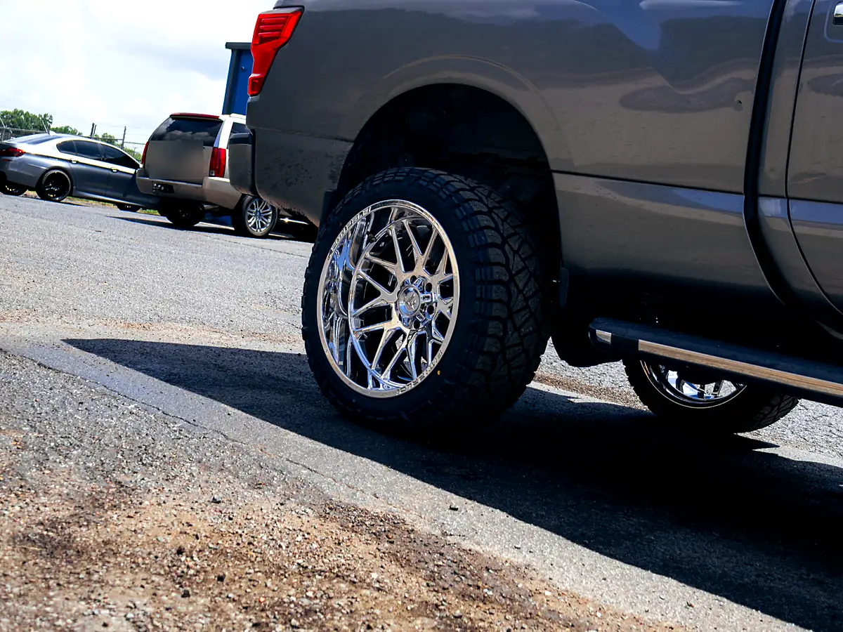 Rear wheel of a gray Nissan Titan XD on a 3 inch Rough Country lift with a chrome Fittipaldi wheel and Predator tire