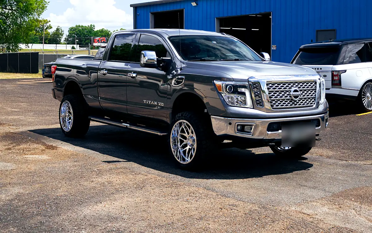 Gray Nissan Titan XD on a 3 inch Rough Country lift with chrome Fittipaldi wheels outside the Wheels Up Front shop