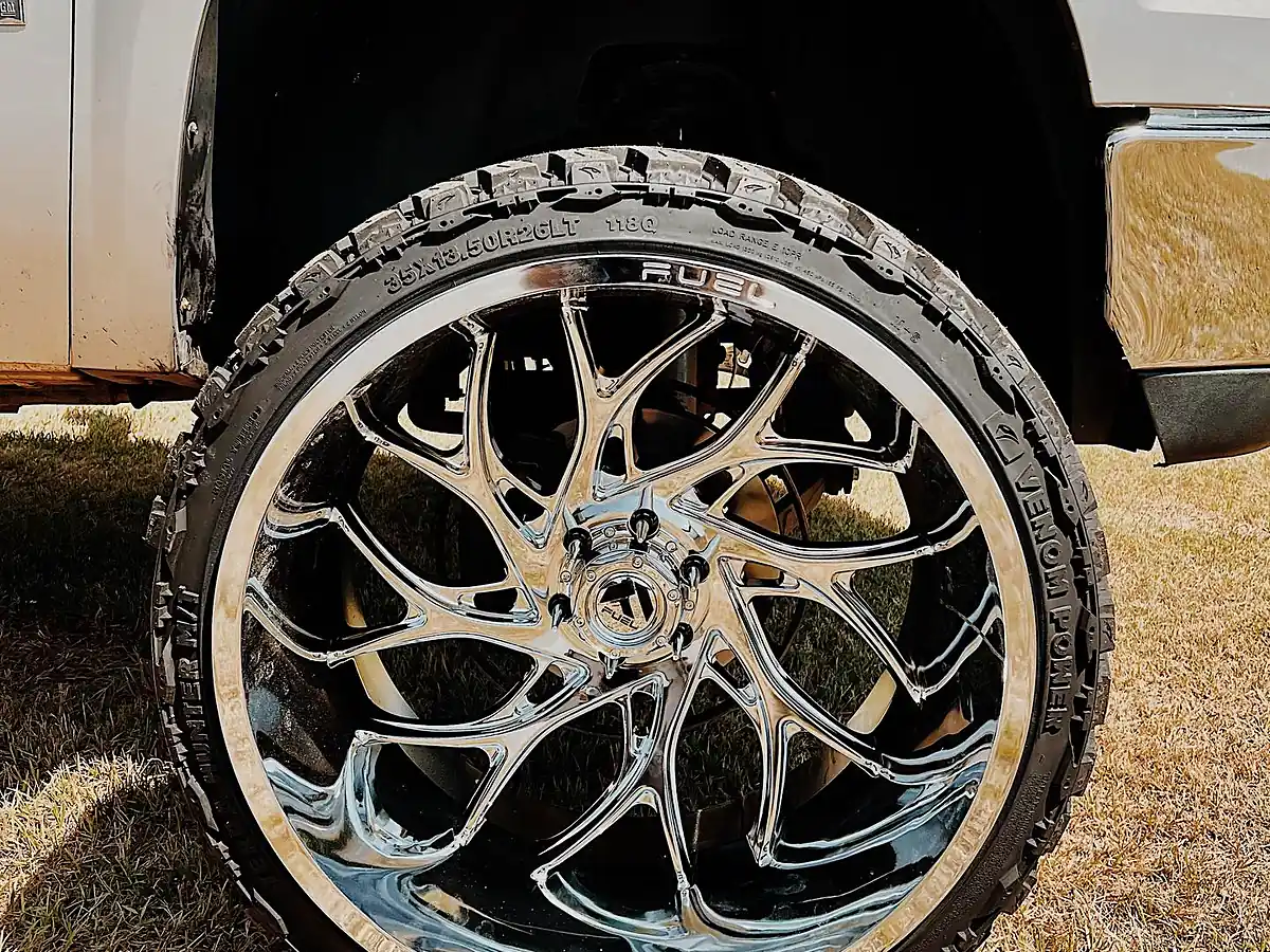 14 inch wide chrome Fuel wheel with a mud-terrain tire on a lifted silver GMC Sierra