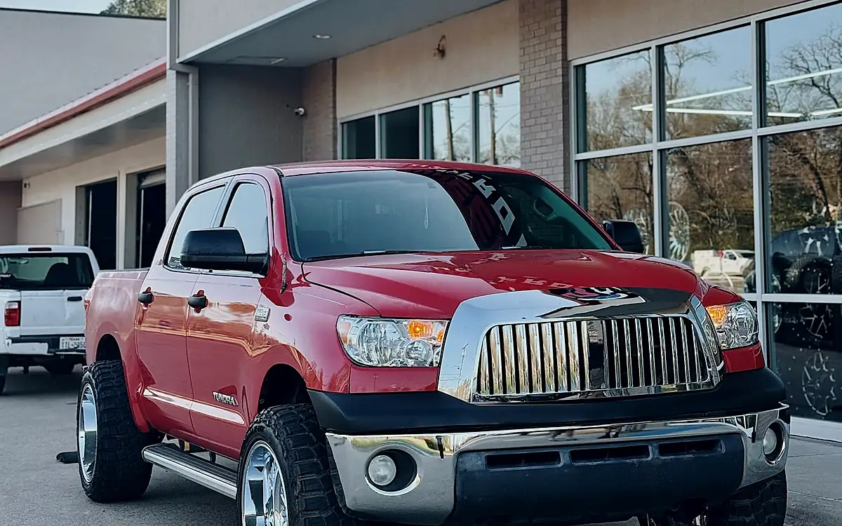 Red Toyota Tundra on 22x12 chrome Fuel Triton wheels and mud-terrain tires outside the Wheels Up Front shop in Tyler