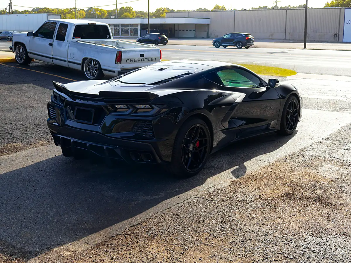 Black Corvette C8 parked at the Wheels Up Front shop with red brake calipers behind black wheels