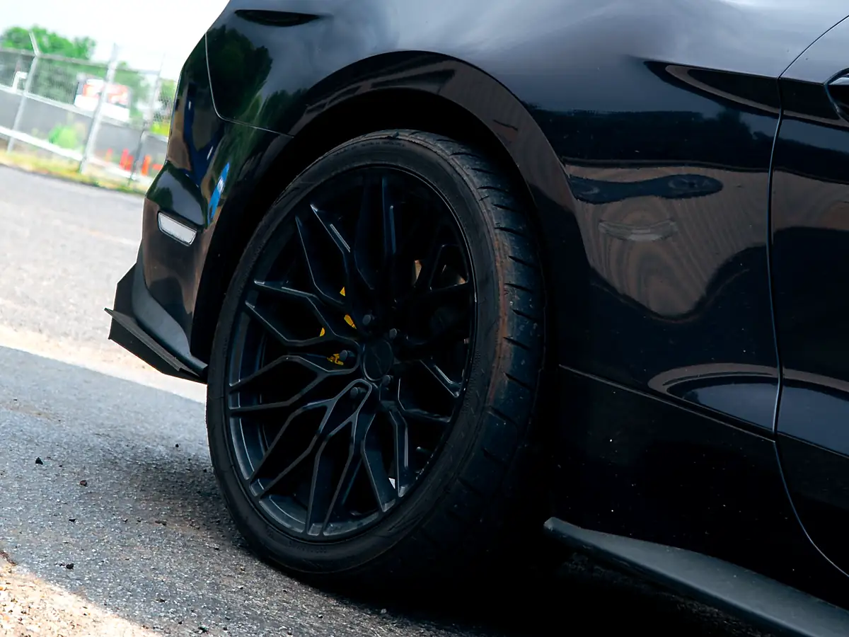 Black wheel and low-profile tire on a black Ford Mustang GT, shot low