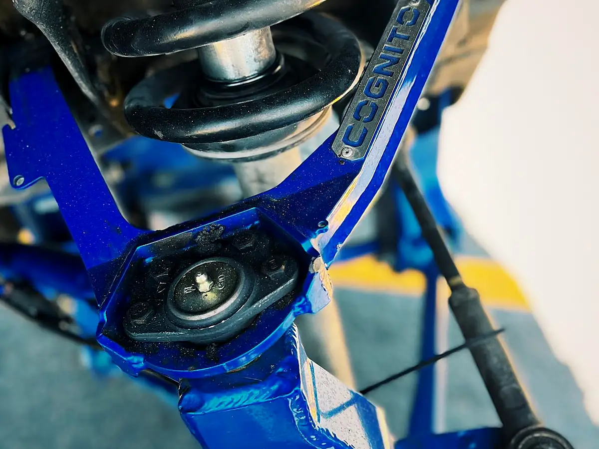 Blue Cognito upper control arm above a coil-over shock on a lifted truck