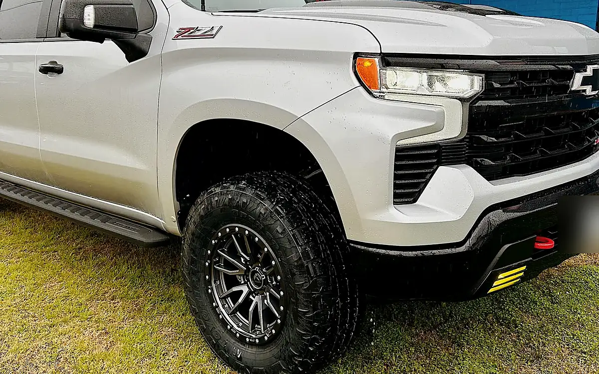 White Chevy Silverado ZR2 front tire on a black Fuel wheel parked on grass at the Wheels Up Front shop