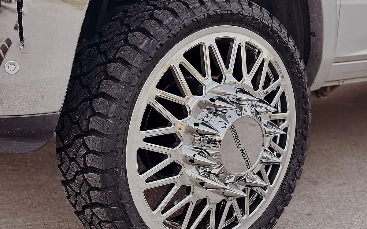 Deep mud-terrain tread on a chrome wheel of a white Ram at the Wheels Up Front shop in Tyler