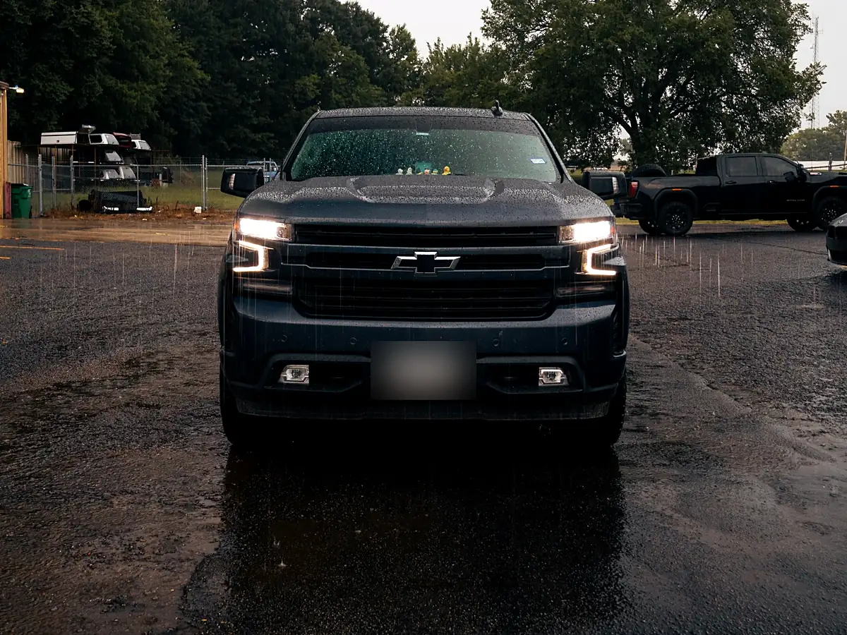 Front view of a leveled gray Chevy Silverado 1500 sitting flat in the rain