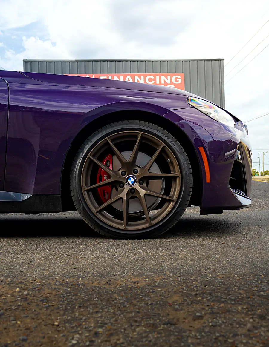 Bronze wheel with a red brake caliper on a purple BMW outside the Wheels Up Front shop