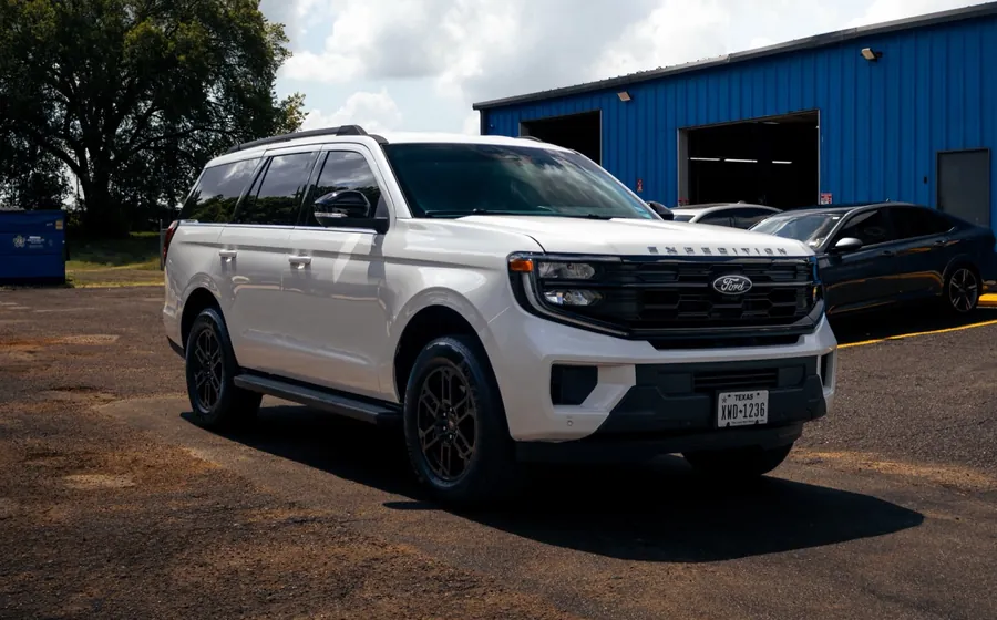 White Ford Expedition, leveled, on dark bronze wheels outside the Wheels Up Front shop in Longview