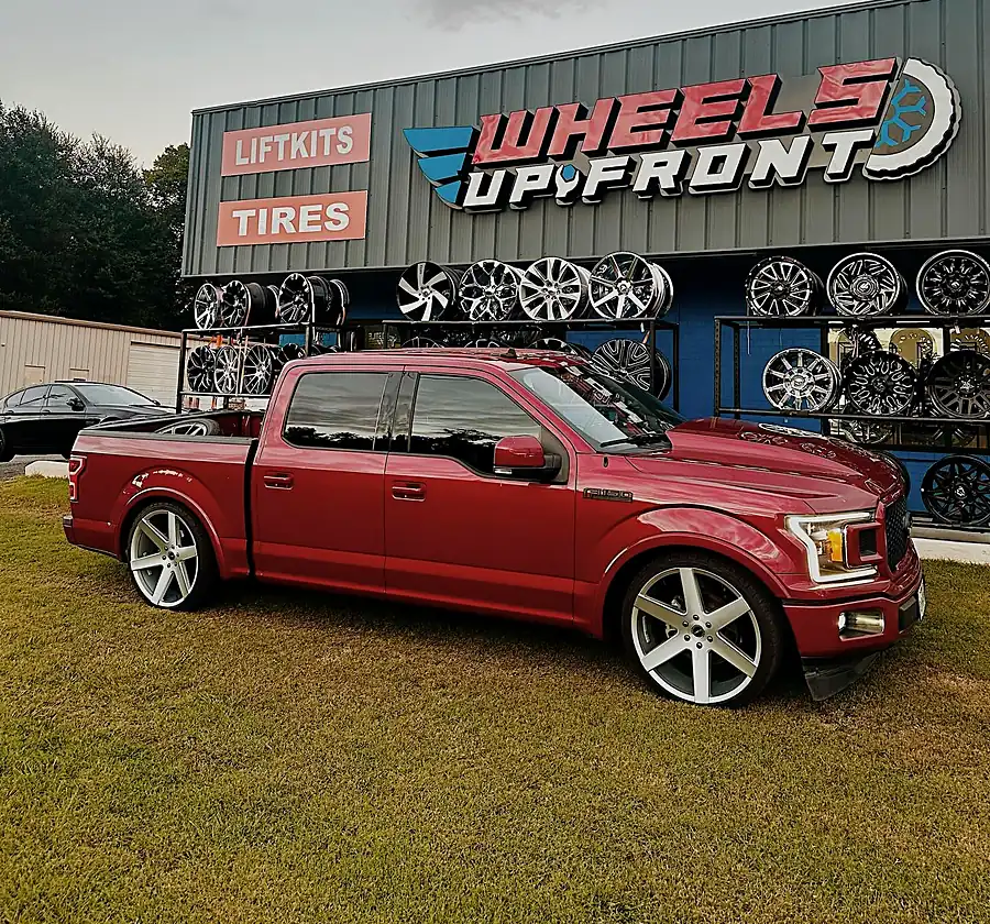 Lowered red Ford F-150 on large silver wheels outside the Wheels Up Front shop