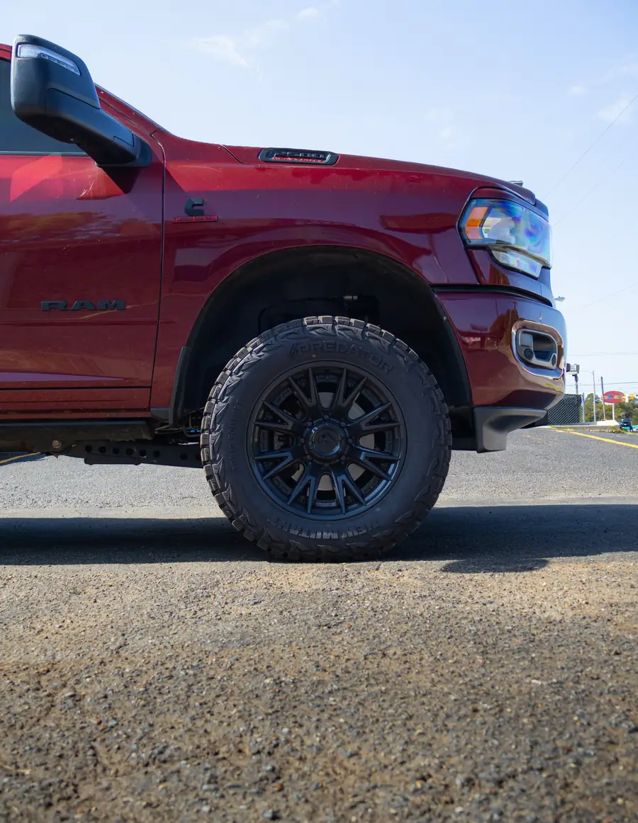 Front wheel and fender of a leveled red Ram 2500 on a black Fuel wheel and 35 inch tire, shot low